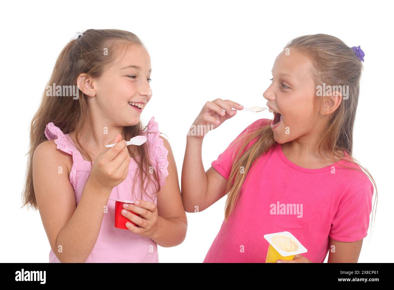 deux petites filles mignonnes mangeant du yaourt sur fond blanc Banque D'Images