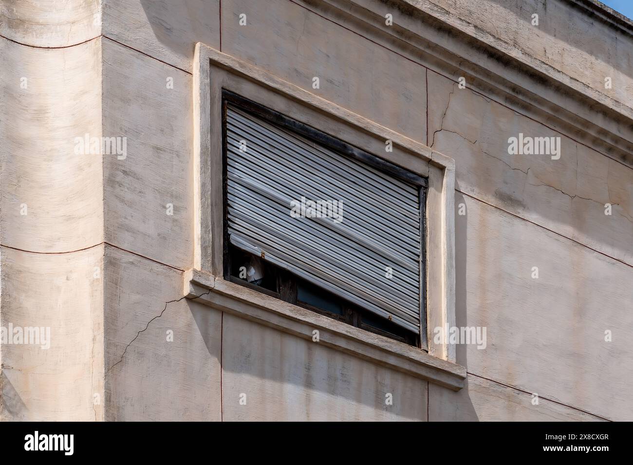 Gros plan d'une façade avec fenêtre et volet incliné endommagé, défectueux Banque D'Images