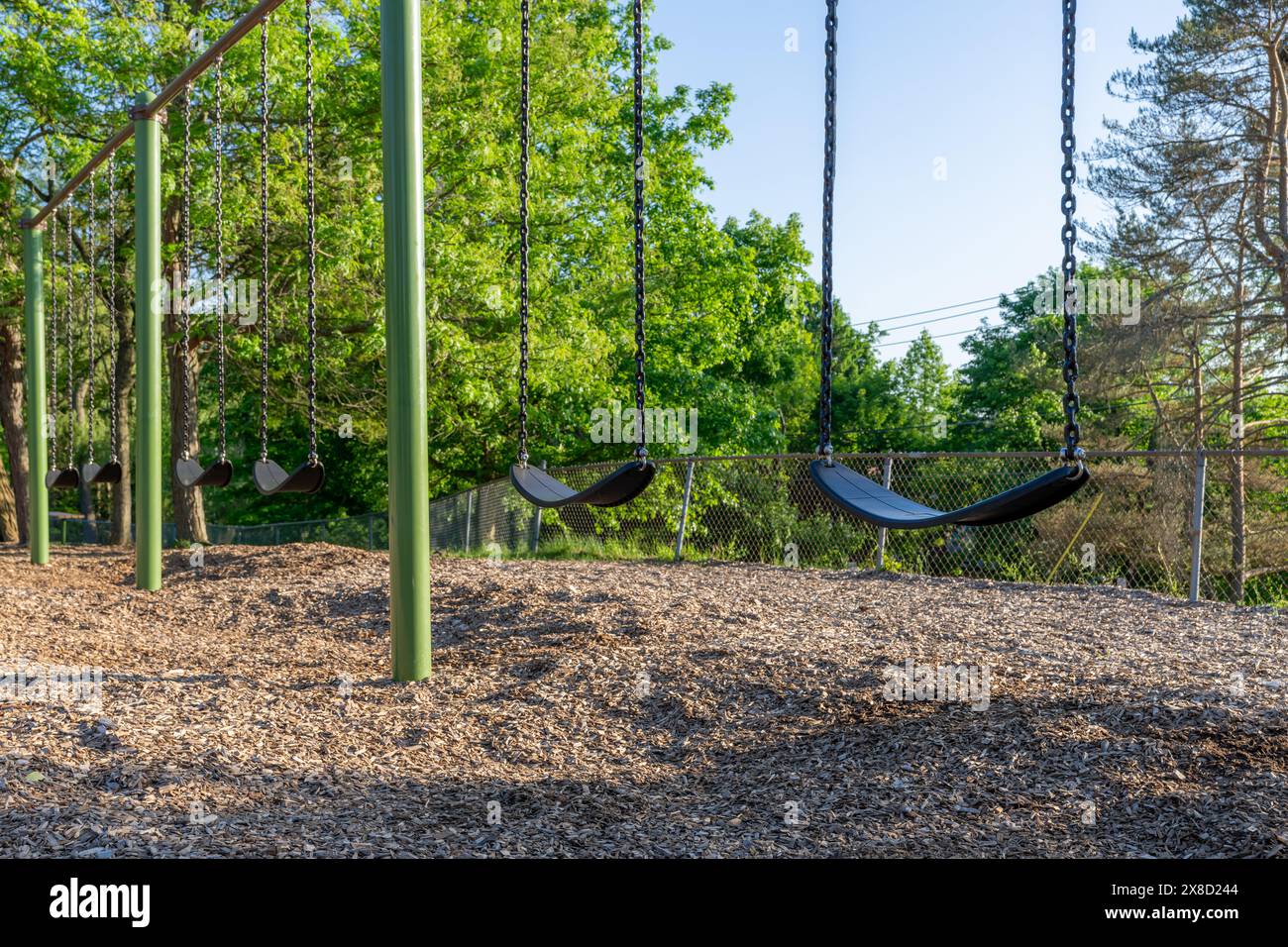 École élémentaire typique des États-Unis, parc municipal, balançoires de terrain de jeu avec surface de chute de sécurité en fibre de bois d'ingénierie. Banque D'Images