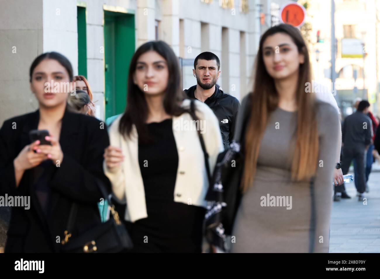 Homme caucasien marche derrière les trois filles parlantes dans la rue de la ville Banque D'Images