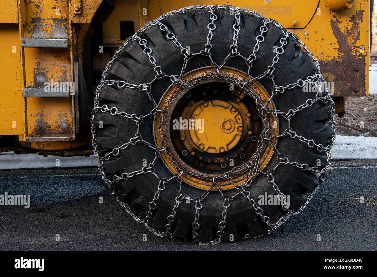 Chaînes à neige sur la roue d'un chasse-neige dans les montagnes californiennes, utilisées pour empêcher le glissement sur les routes verglacées lors du déneigement. Banque D'Images