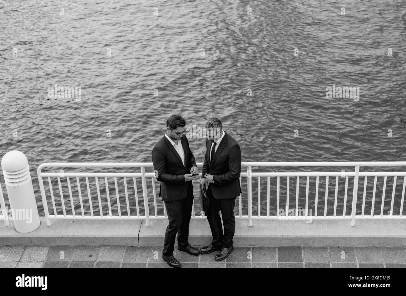 Homme d'affaires du Moyen-Orient joyeux marchant dans la rue vers un immeuble de bureaux moderne. Portrait de personnes d'affaires réussies à l'extérieur, parlant ensemble Banque D'Images