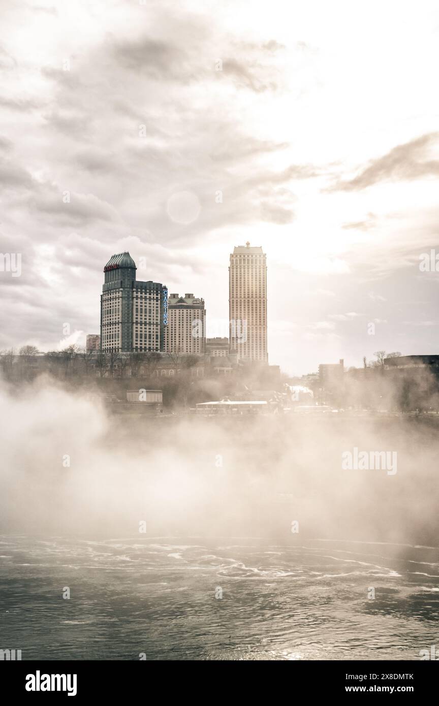 Côté canadien des chutes du Niagara enveloppé dans la brume. Les bâtiments imposants jettent un œil à travers les nuages, créant un air de mystère. Idéal pour le paysage de voyage. Banque D'Images