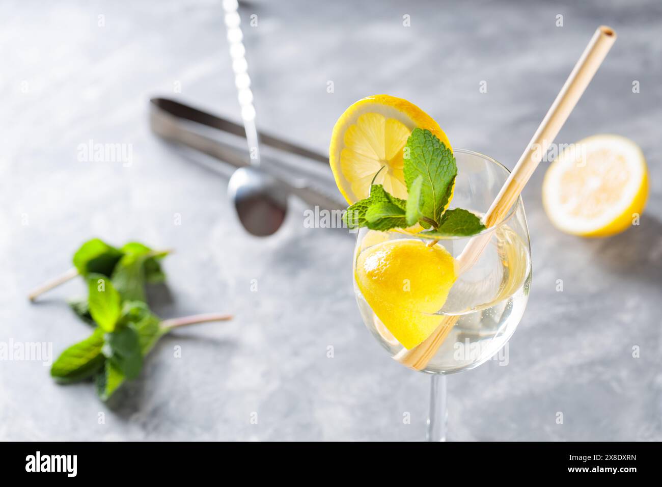 Cocktail Hugo Spritz avec menthe, citron et paille de bambou sur fond béton Banque D'Images