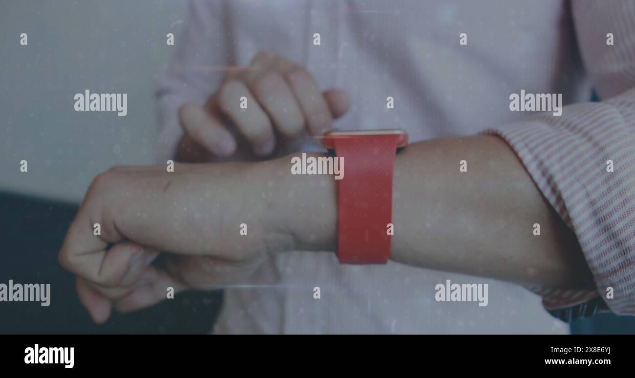 Partenaire masculin caucasien ajustant la smartwatch rouge sur le poignet, portant une chemise rose clair Banque D'Images