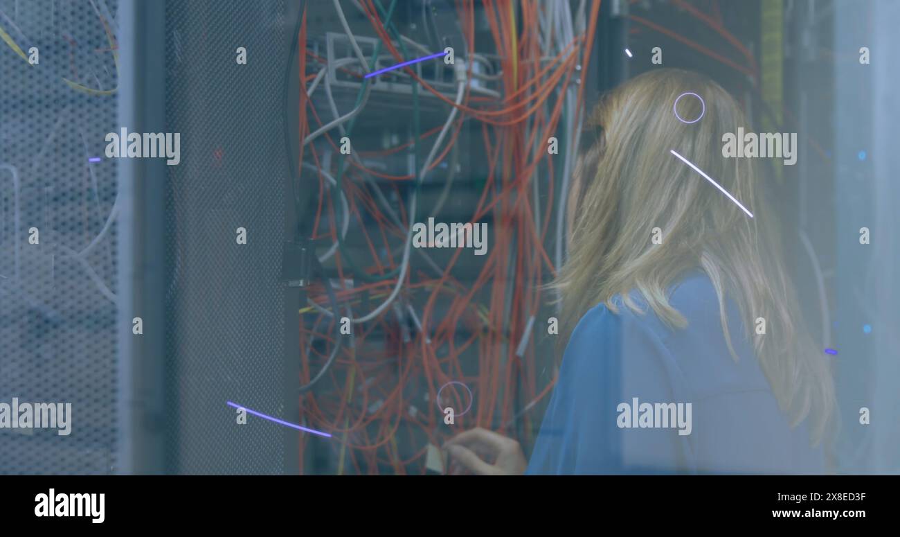 Femme caucasienne portant une chemise bleue, examinant les câbles du serveur Banque D'Images