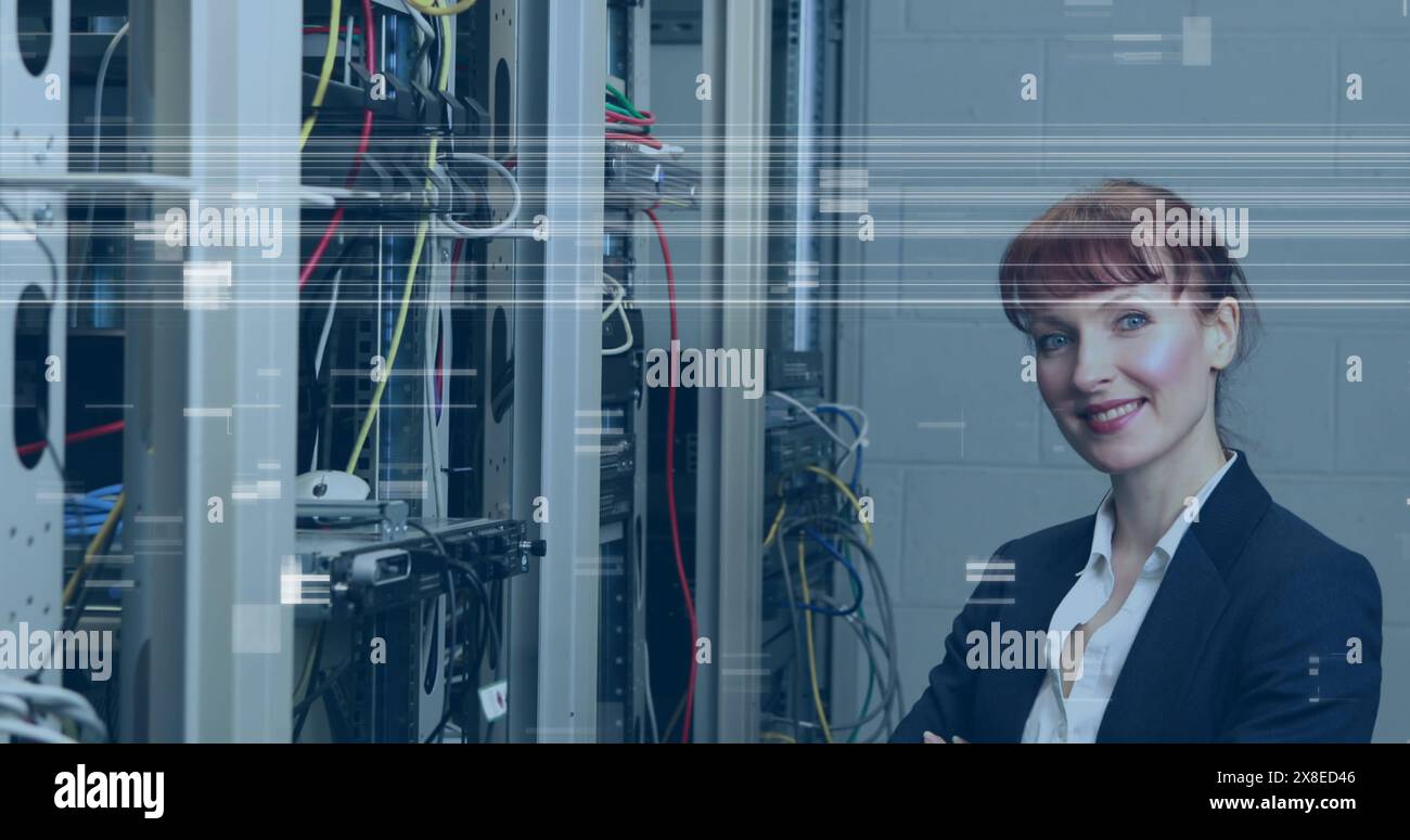 Femme caucasienne debout devant des racks de serveurs, souriante Banque D'Images
