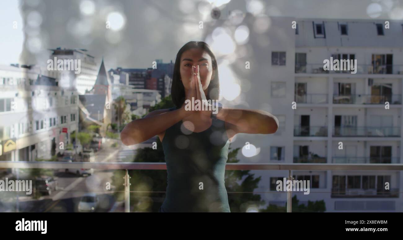 Image de lumières brillantes sur une femme biraciale pratiquant le yoga Banque D'Images