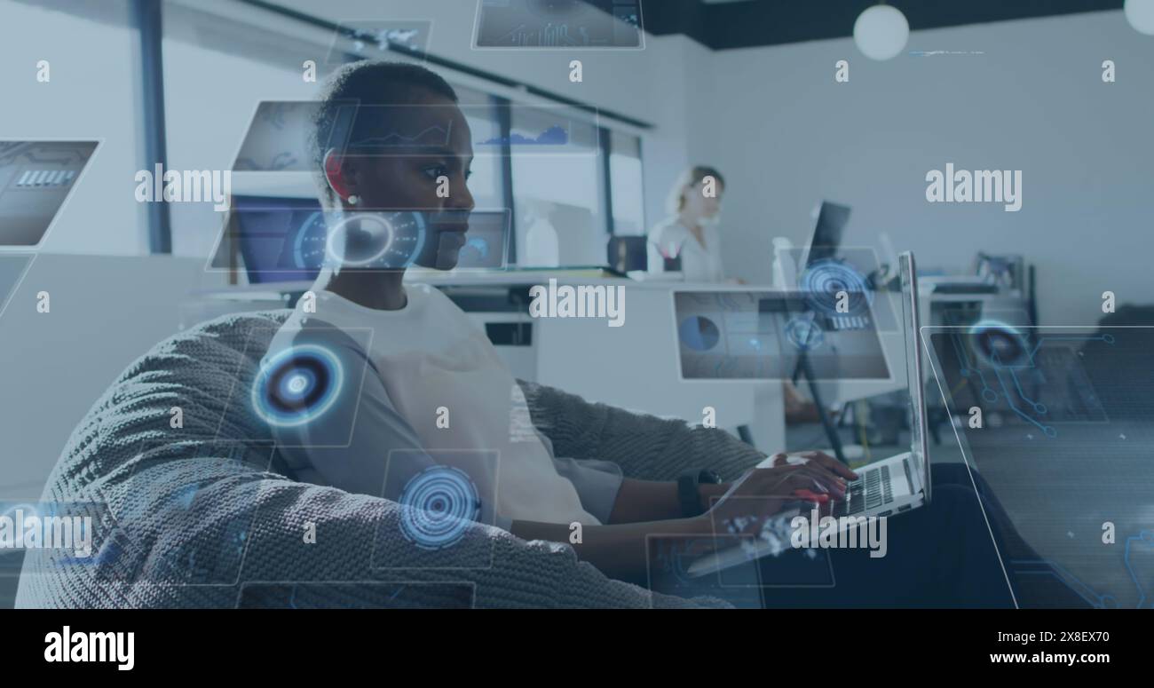 Image de scanners ronds et de traitement de données sur une femme afro-américaine utilisant un ordinateur portable au bureau Banque D'Images