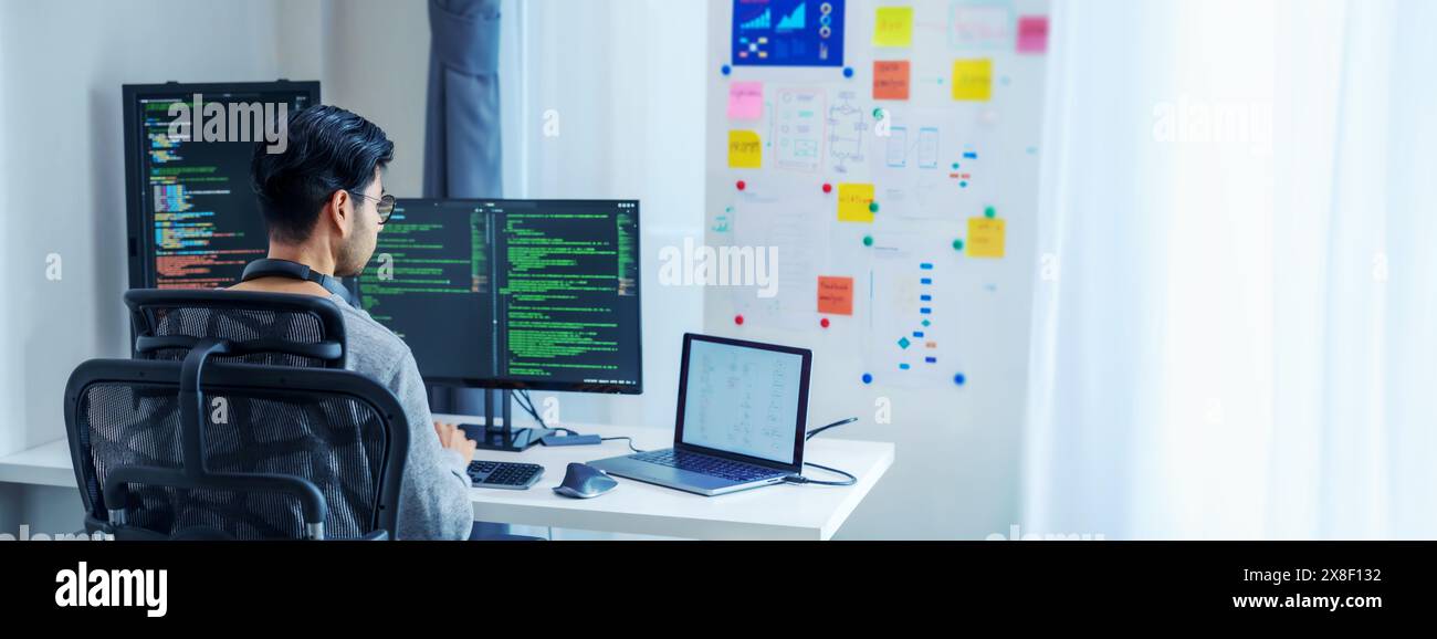 Développeurs de logiciels asiatiques travaillant sur plusieurs écrans affichant le code et les diagrammes d'application dans un bureau moderne Banque D'Images