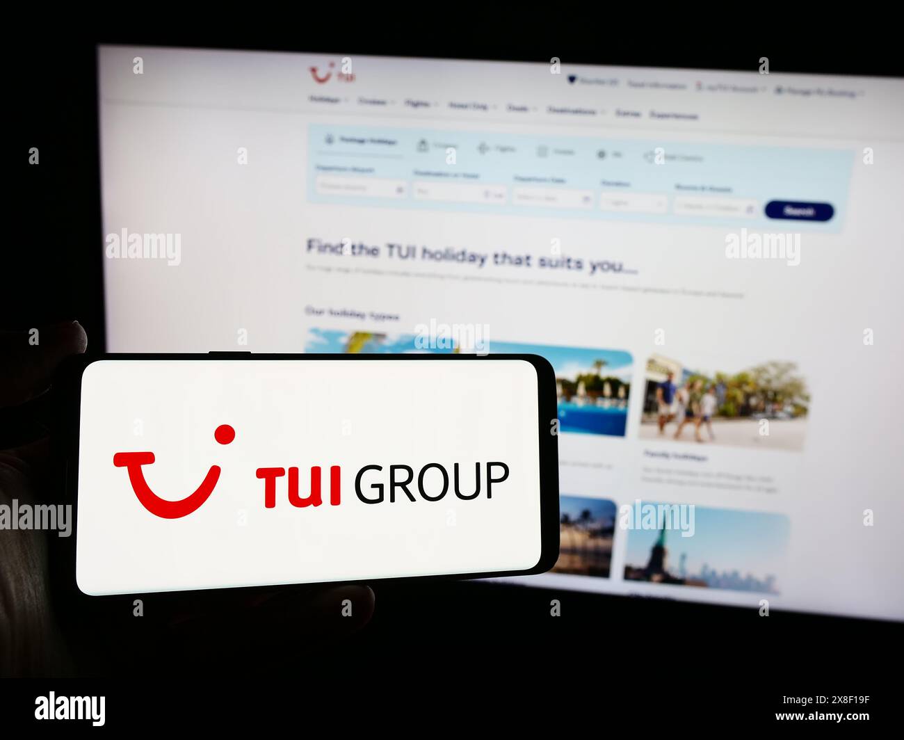 Personne tenant un smartphone avec le logo de la société allemande de voyage et de tourisme TUI AG en face du site Web. Concentrez-vous sur l'affichage du téléphone. Banque D'Images