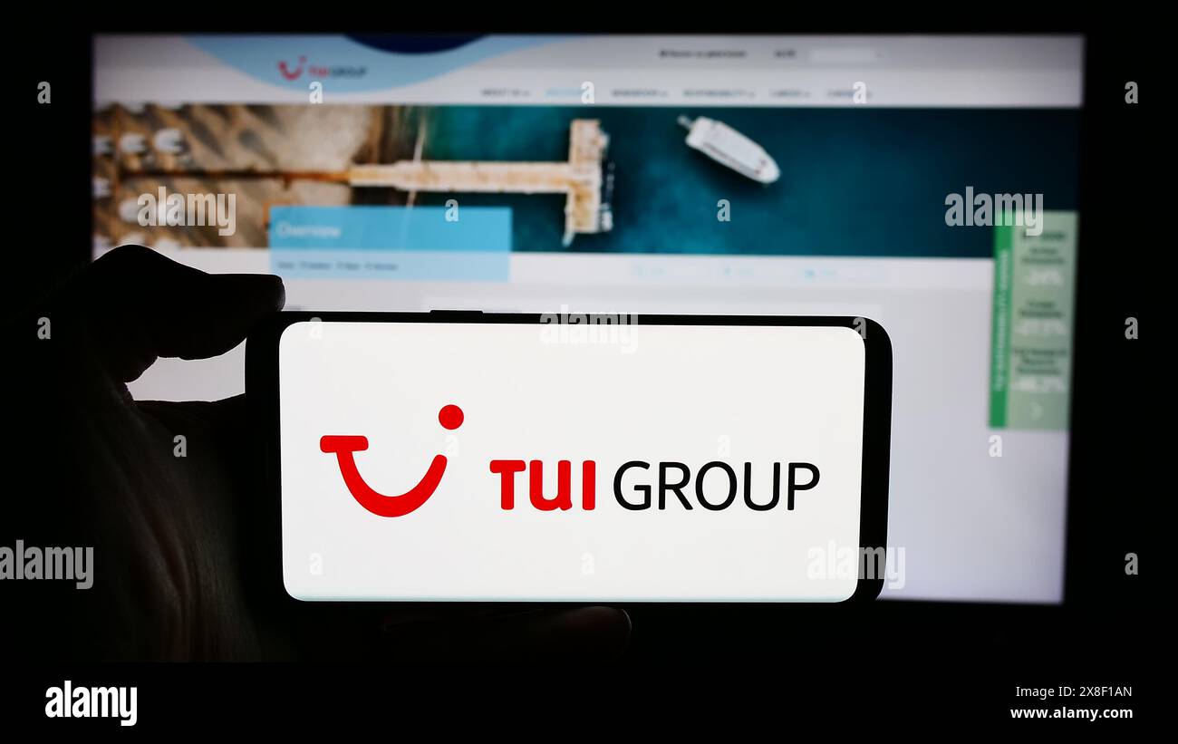 Personne tenant le téléphone portable avec le logo de la société allemande de voyage et de tourisme TUI AG devant la page Web de l'entreprise. Concentrez-vous sur l'affichage du téléphone. Banque D'Images