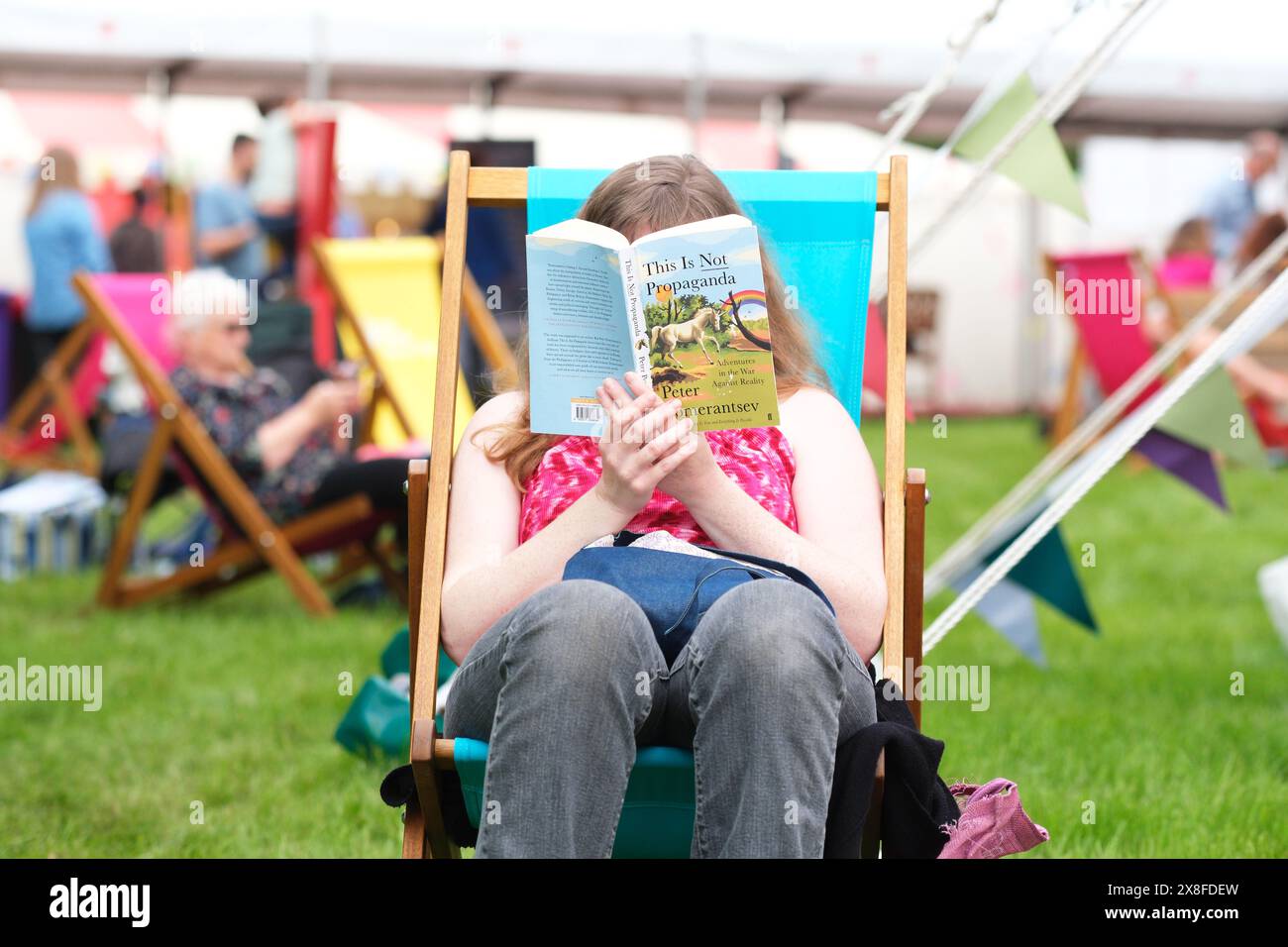 Hay Festival, Hay on Wye, Powys, pays de Galles, Royaume-Uni – samedi 25 mai 2024 – Météo Royaume-Uni - temps ensoleillé ce matin le jour 3 de cette année Hay Festival avec les visiteurs profitant d'une chance de se détendre sur les pelouses du Festival entre les événements et lire un livre de l'auteur Peter Pomerantsev - photo Steven May / Alamy Live actualités Banque D'Images