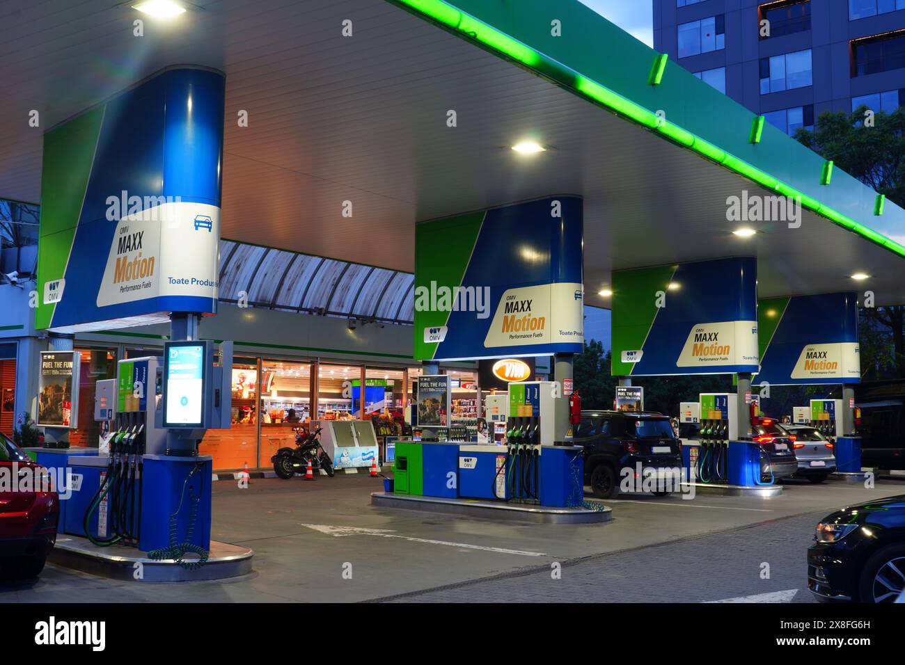 Bucarest, Roumanie - 13 mai 2024 : station d'essence de la société OMV avec des pompes à essence et des voitures de ravitaillement dans la soirée Banque D'Images