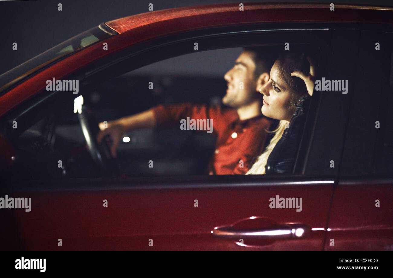 Femme, sourire et couple transport en voiture la nuit pour célébrer anniversaire, date ou voyage en voiture pour des vacances surprise. Heureux, les gens et l'homme conduisent Banque D'Images