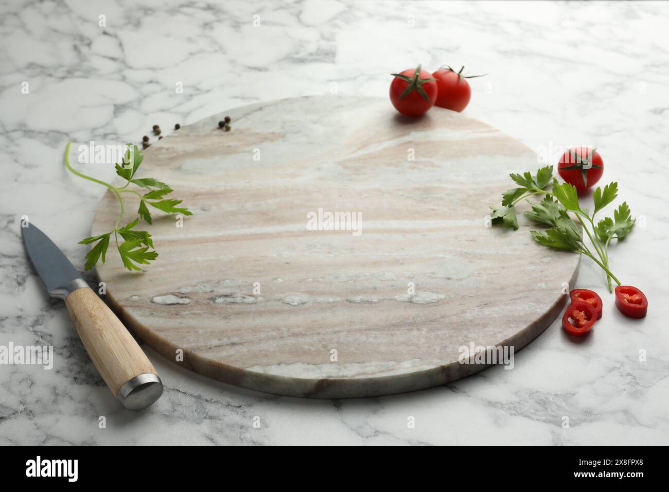 Planche à découper, persil, poivre et tomates sur table en marbre blanc. Espace pour le texte Banque D'Images