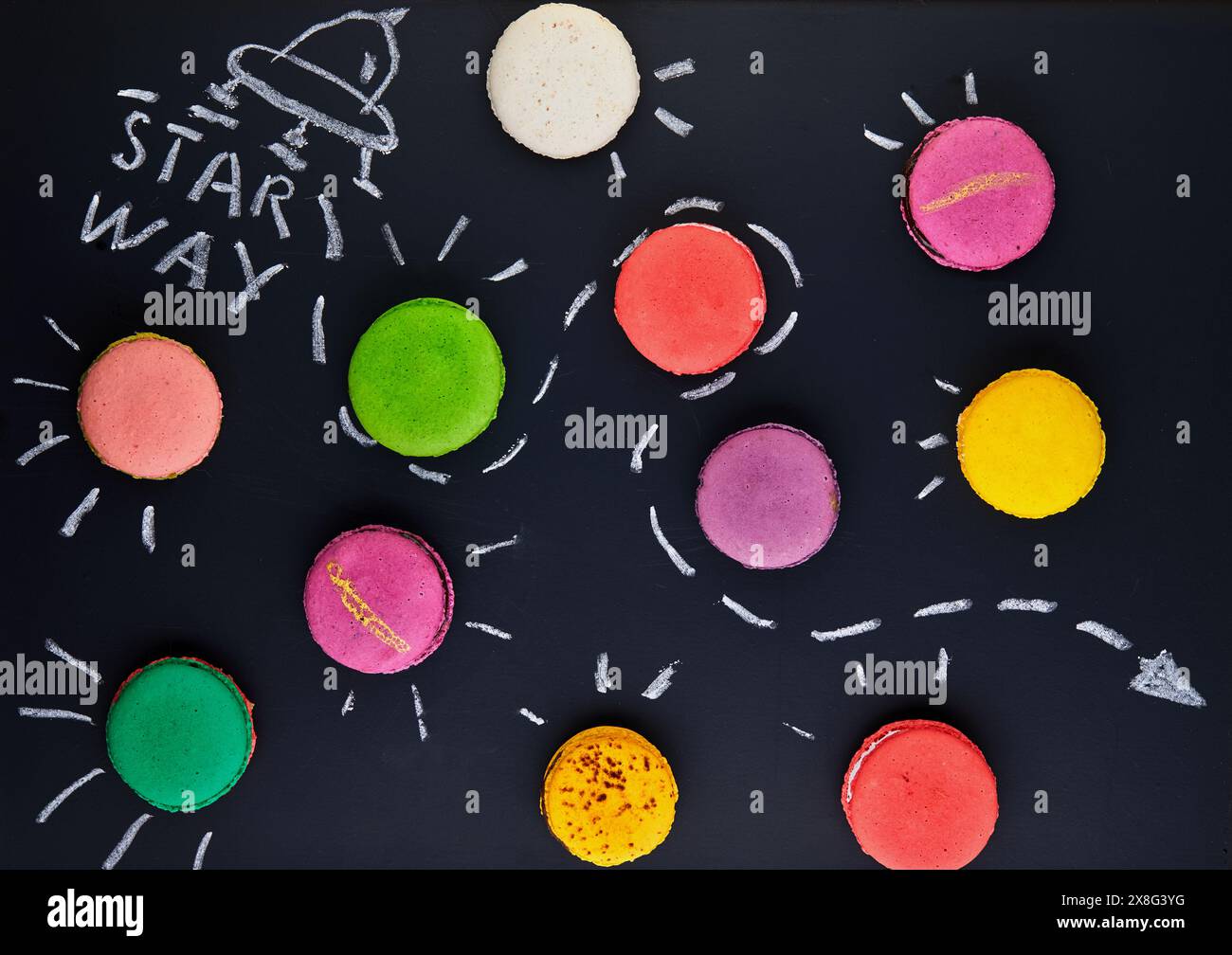 Une peinture fascinante de macarons multicolores ressemblant à des organismes, avec des pétales colorés sur une surface noire, créant un beau motif qui peigne Banque D'Images