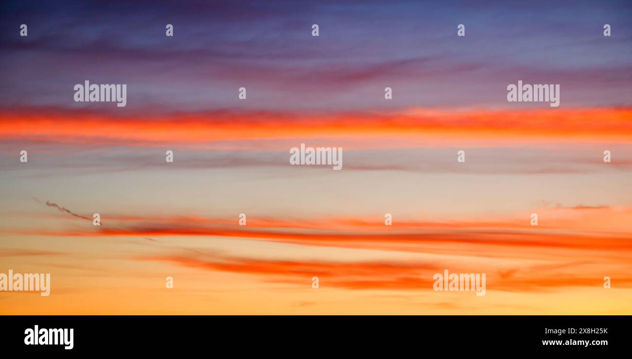 Un coucher de soleil serein peignant le ciel avec des teintes orange, bleu et violet, évoquant un sentiment de calme. Idéal pour le contenu de relaxation. Banque D'Images