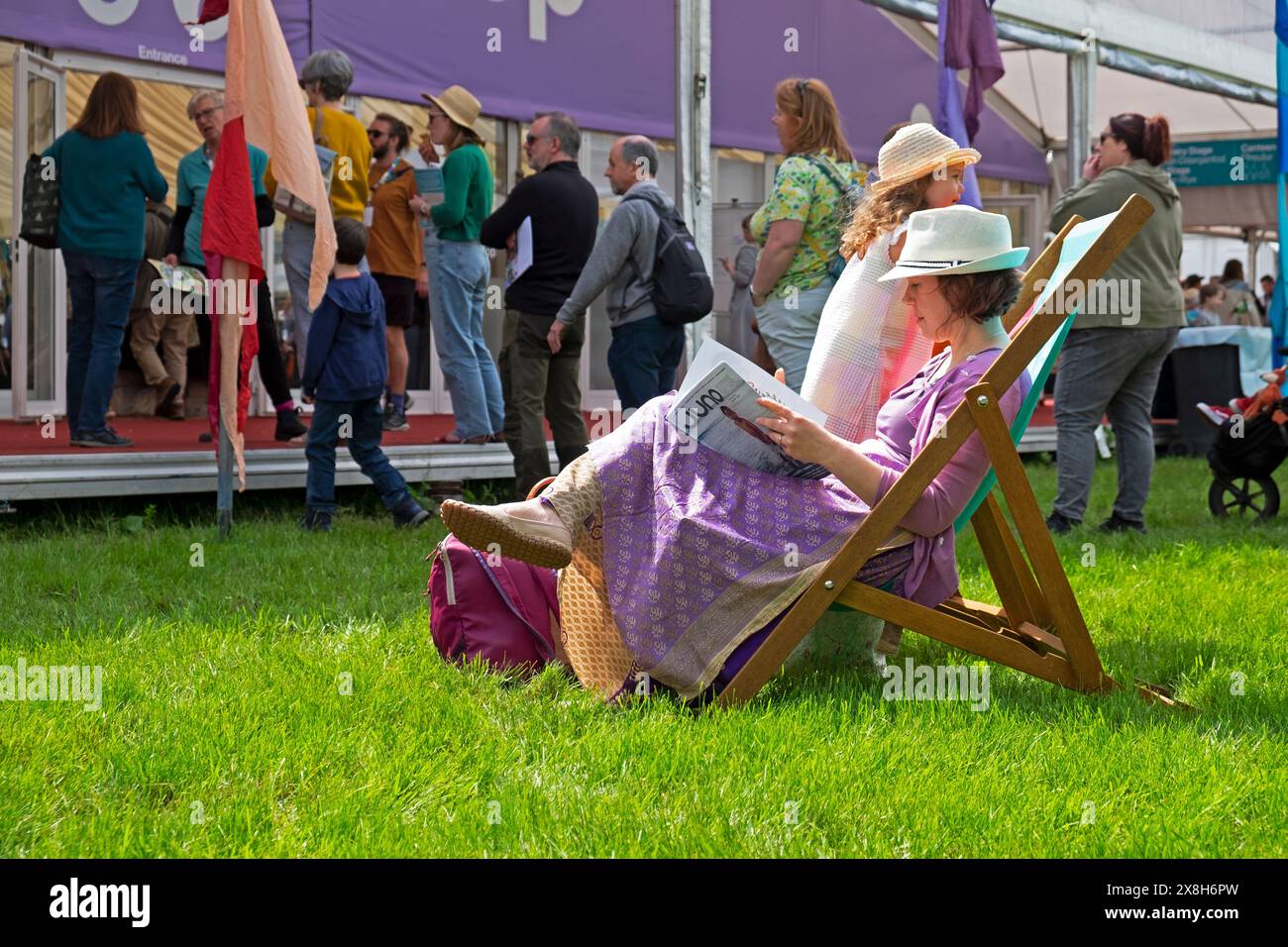 Femme mère enfant chapeaux de paille relaxant lecture dans un transat à l'extérieur de la librairie au Hay Festival mai 2024 Hay-on-Wye pays de Galles Royaume-Uni Grande-Bretagne KATHY DEWITT Banque D'Images