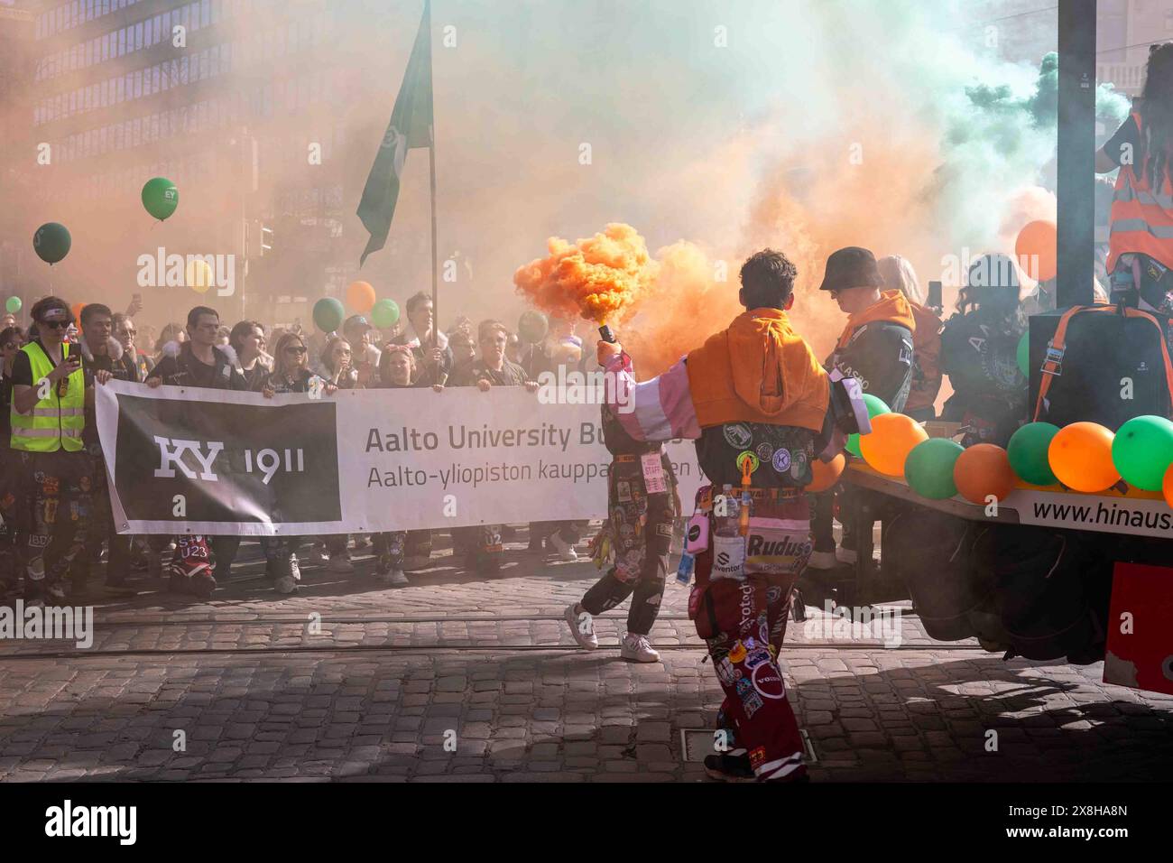 Étudiant en commerce de l'Université Aalto tenant une grenade fumigène orange lors du défilé de la veille du jour de mai à Helsinki, Finlande Banque D'Images