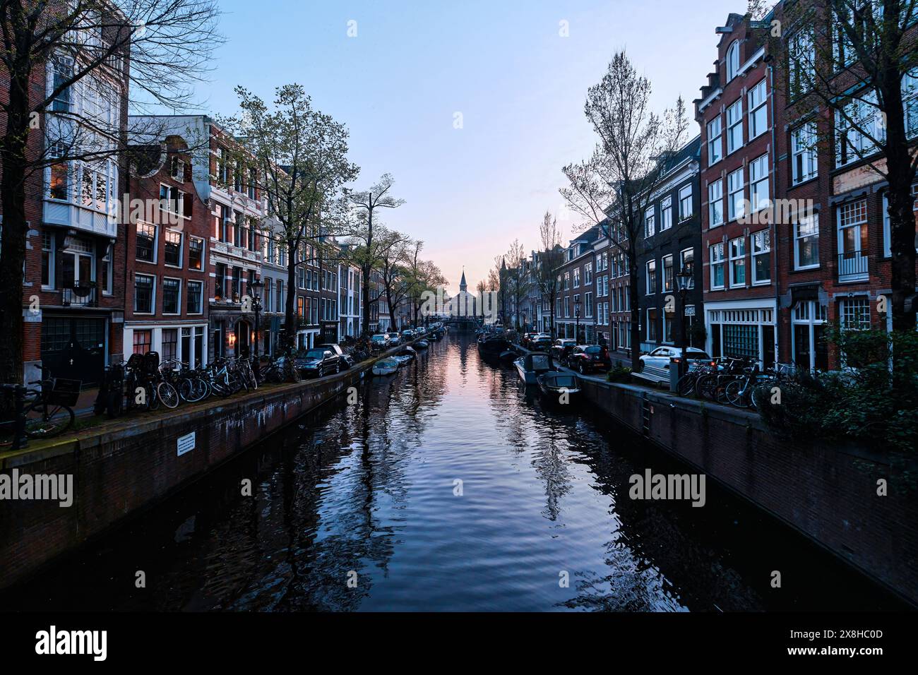 Pays-Bas, Amsterdam - 10 avril 2024 : maisons de canal d'Amsterdam, vélos et pont dans le quartier Jordaan au crépuscule Banque D'Images