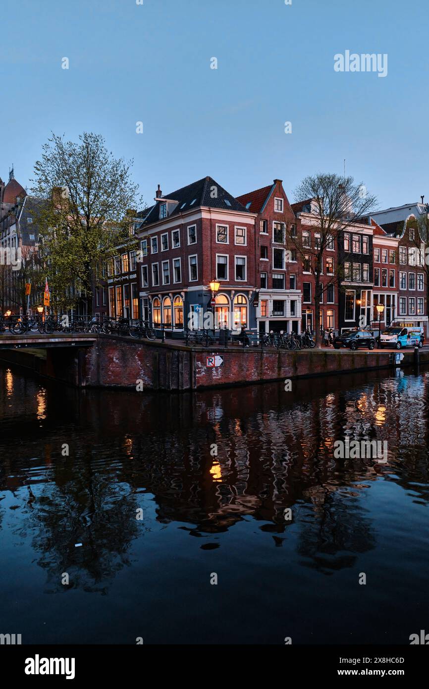 Pays-Bas, Amsterdam - 10 avril 2024 : maisons de canal d'Amsterdam, vélos et pont dans le quartier Jordaan au crépuscule Banque D'Images