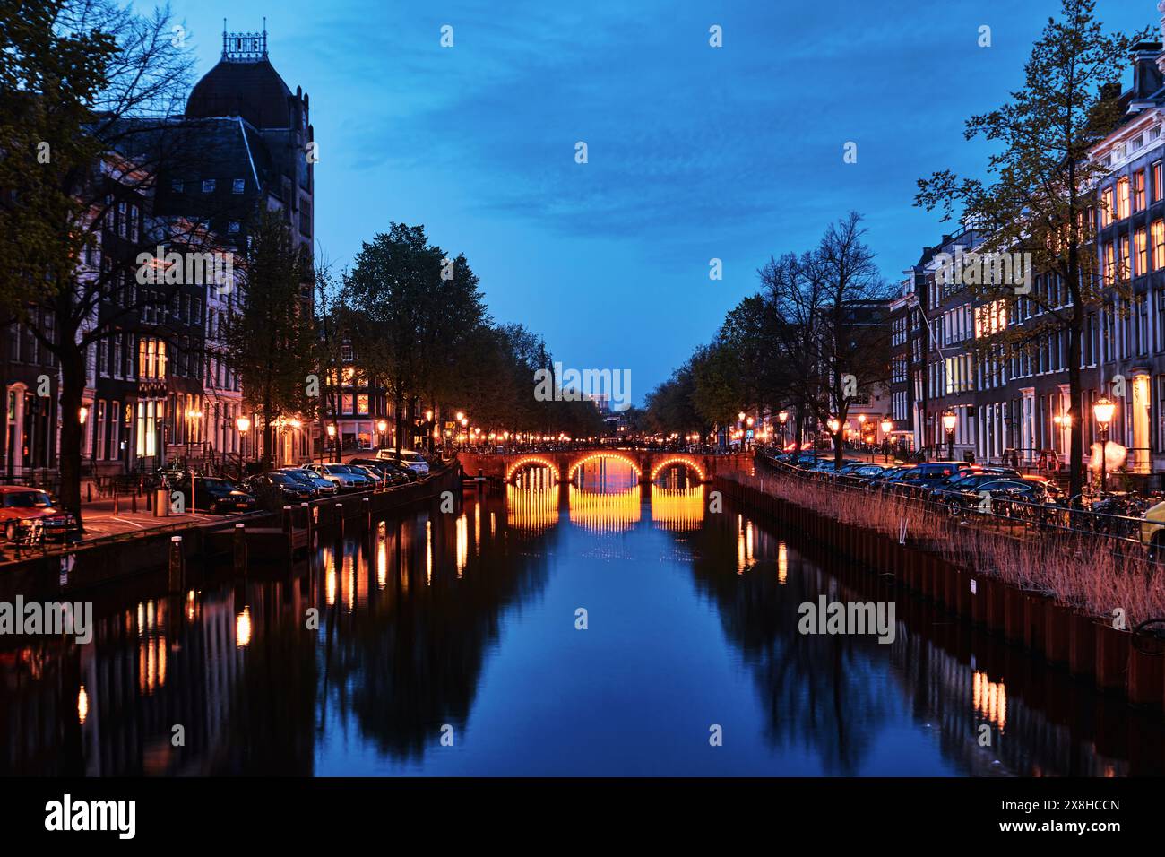 Pays-Bas, Amsterdam - 10 avril 2024 : maisons de canal d'Amsterdam, vélos et pont dans le quartier Jordaan au crépuscule Banque D'Images