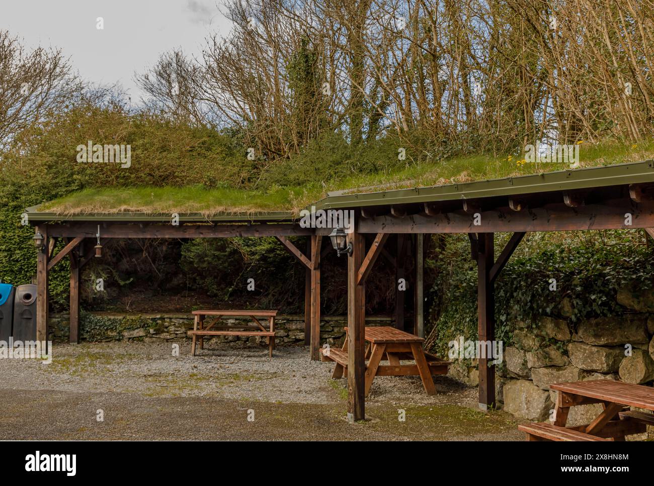 Coin salon extérieur unique avec un toit en herbe écologique en bois avec des bancs de pique-nique en bois en dessous Banque D'Images