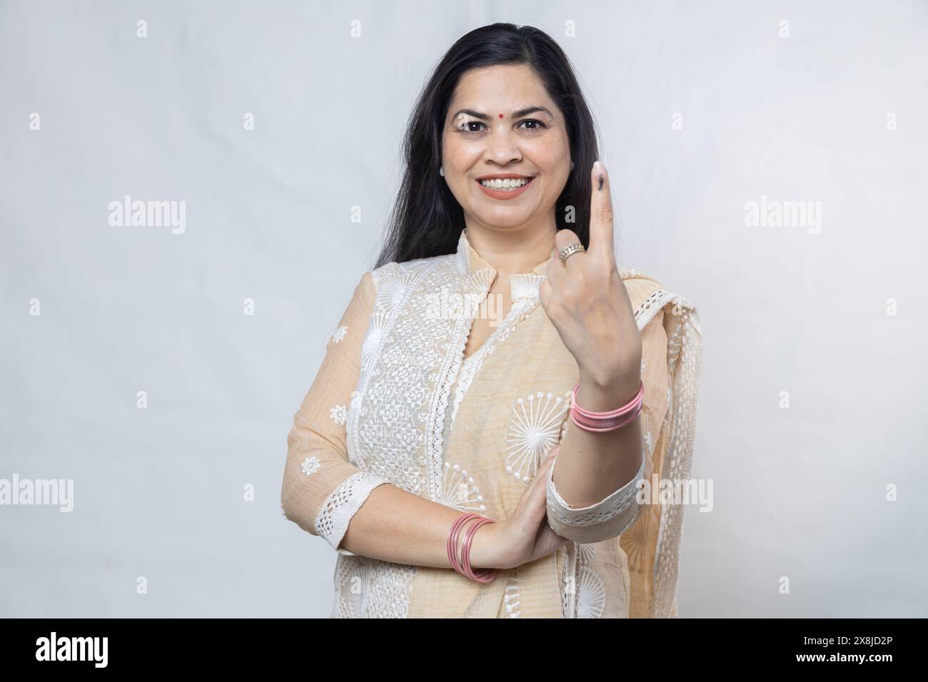 Election en inde. Portrait d'une femme heureuse portant le hijab montre le doigt marqué avec de l'encre après avoir voté debout isolé sur fond blanc, Polli Banque D'Images