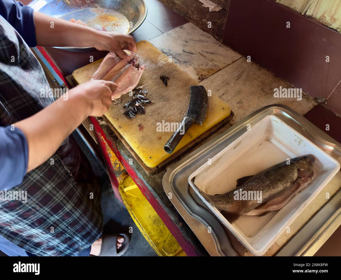 Le chef coupe du poisson d'eau douce dans la cuisine d'un restaurant Banque D'Images
