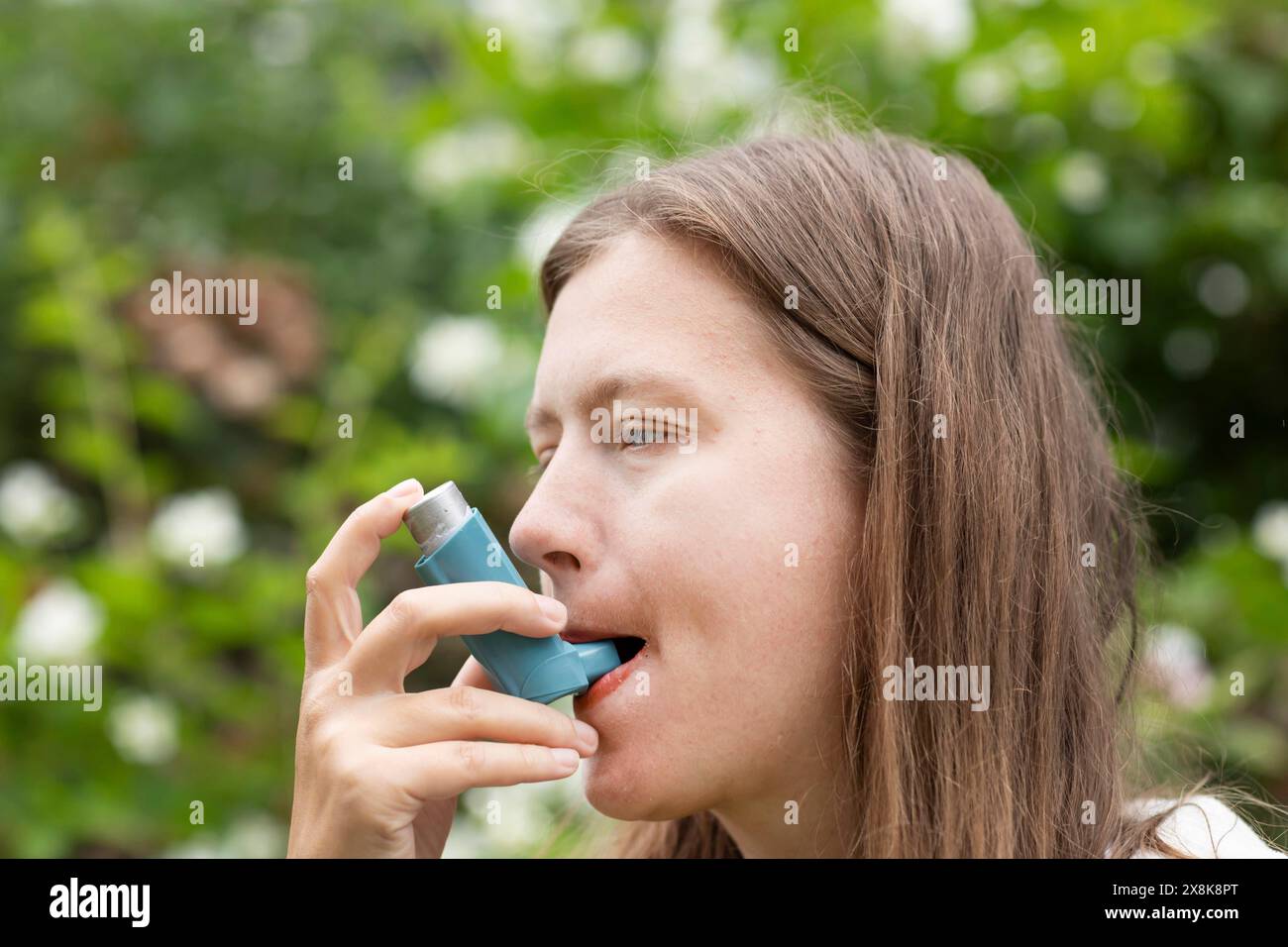 La jeune femme souffre du rhume des foins et inhale l'asthme spray à l'extérieur, Fribourg, Bade-Wuerttemberg, Allemagne Banque D'Images