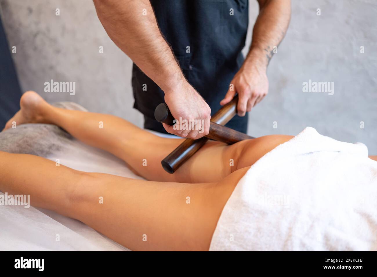 Massage créole avec bâtons de bambou sur les pieds d'une femme dans un salon de spa. Massage par drainage lymphatique des muscles des tibias. Banque D'Images