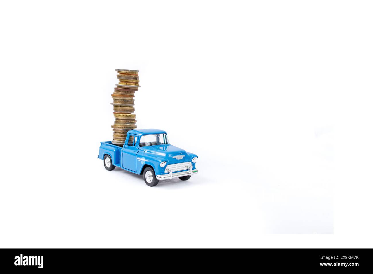 Jouet de ramassage moulé sous pression portant une pile élevée de pièces de monnaie, isolé sur fond blanc, flou Banque D'Images