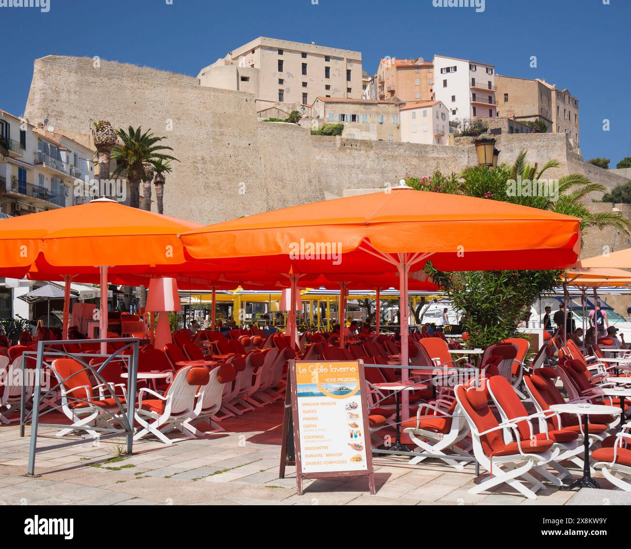 Calvi, haute-Corse, Corse, France. Café coloré sur le bord du port sur le quai Landry sous les murs massifs de la citadelle génoise. Banque D'Images