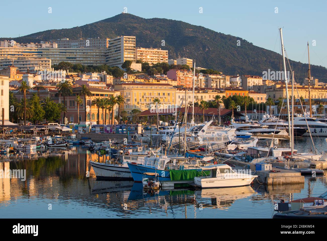 Ajaccio, Corse-du-Sud, Corse, France. Vue sur le port de plaisance de Tino Rossi et le port de pêche, lever du soleil, bateaux reflétés dans l'eau tranquille. Banque D'Images