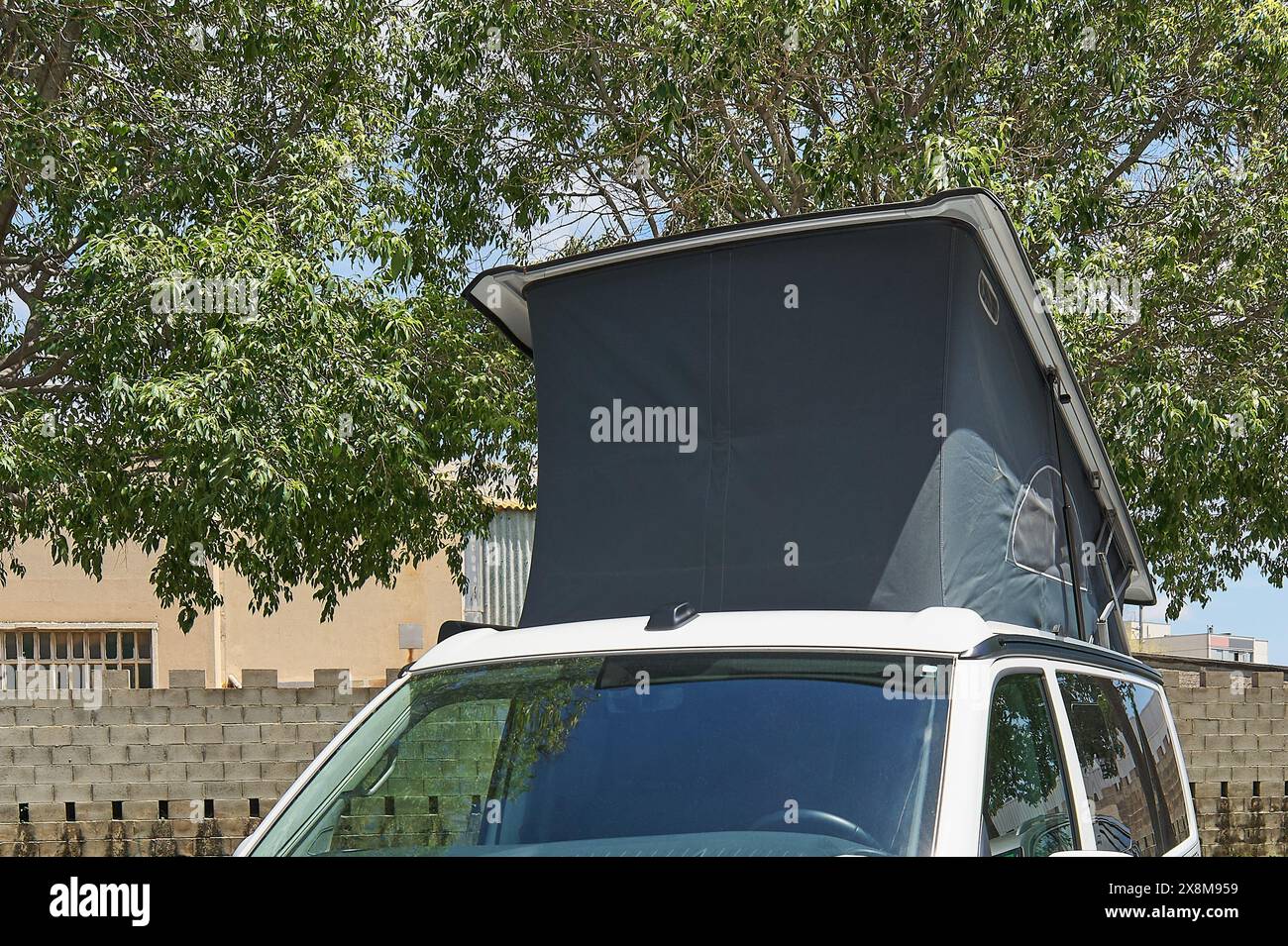 Fourgon camping-car blanc Urban Explorers présentant son toit surélevé au milieu de paysages de rue quotidiens. Banque D'Images