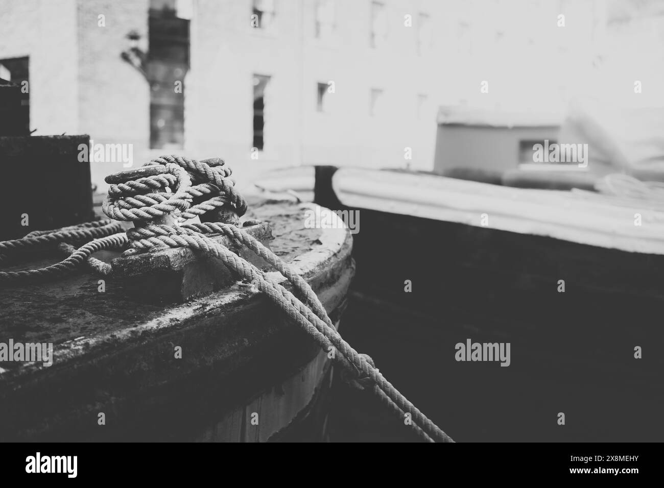 Image N&B d'un bateau amarré avec des cordes nouées détaillées et un environnement industriel, évoquant une sensation rustique et nautique. Castlefield Manchester Royaume-Uni Banque D'Images