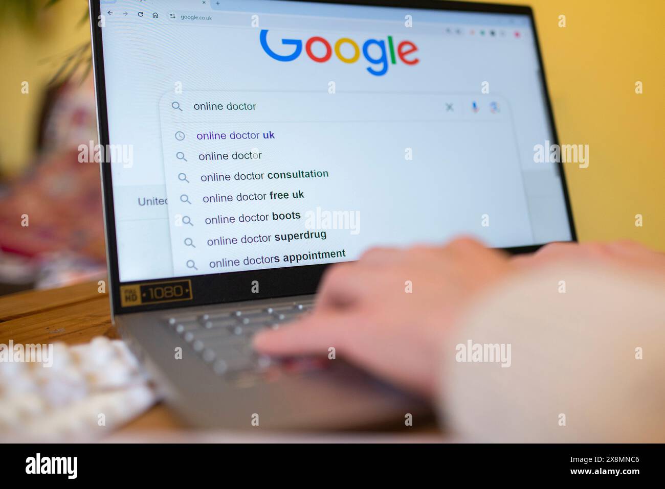 Personne recherchant des services médicaux en ligne au Royaume-Uni sur un ordinateur portable, affichant des suggestions de recherche sur Google. Banque D'Images