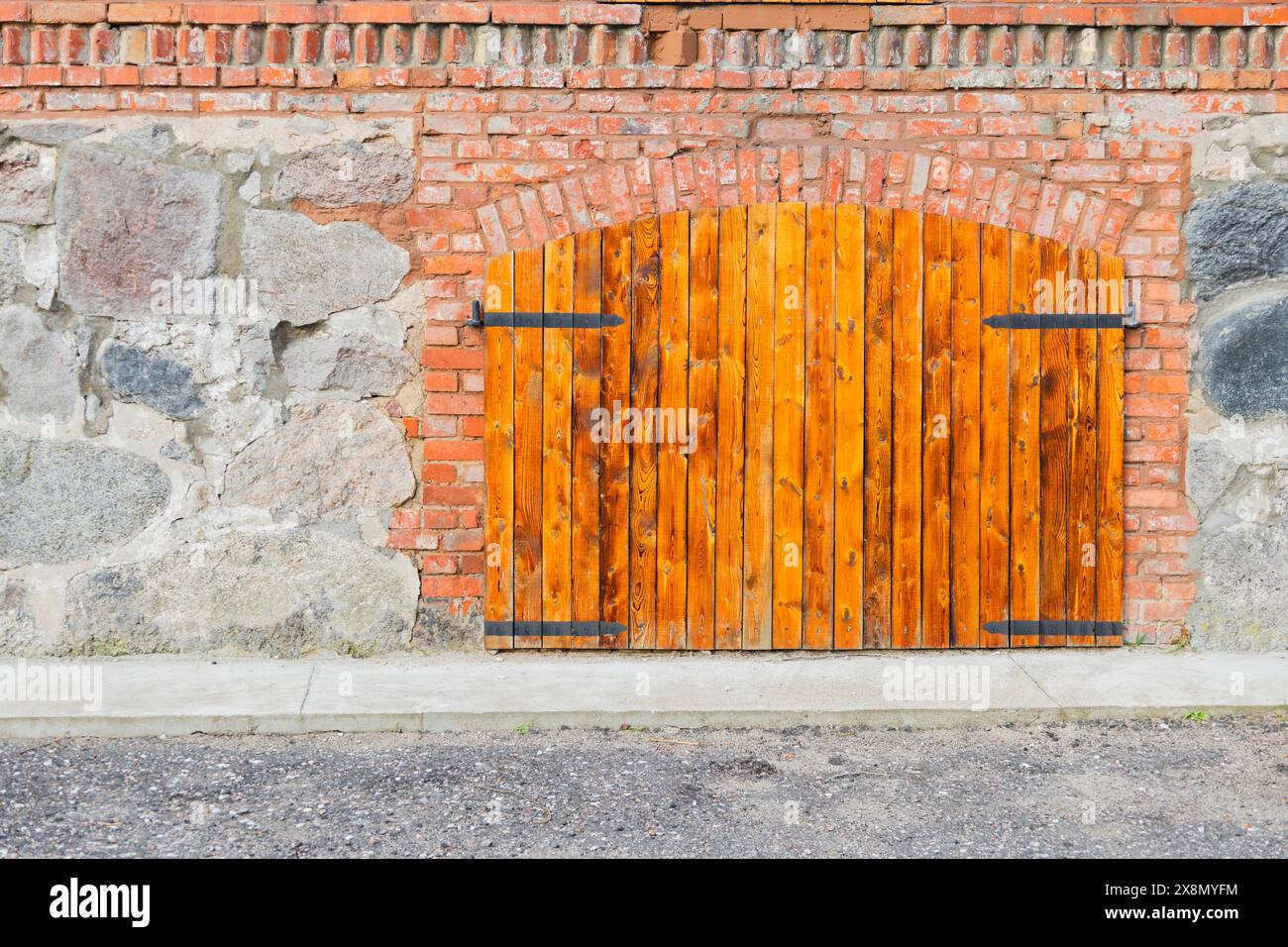 Un bâtiment avec une façade en briques et des volets en bois, surmonté d'un toit violet, se dresse sur une surface de route asphaltée Banque D'Images