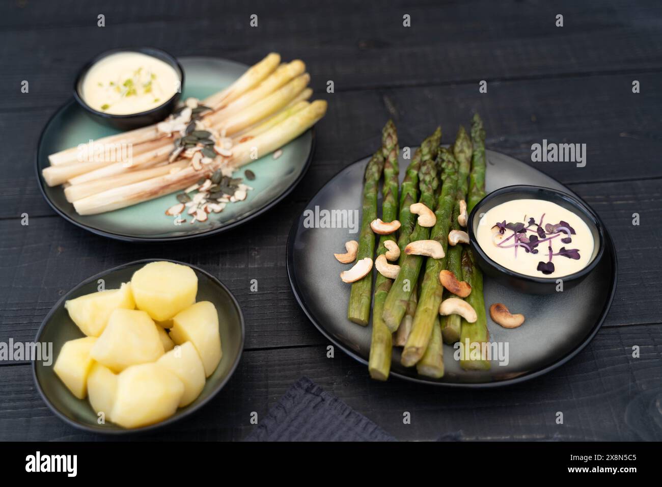 Asperges blanches et vertes servies dans des assiettes foncées avec sauce hollandaise. Les asperges représentant les fibres alimentaires sont très populaires en Allemagne pendant Spargel Banque D'Images