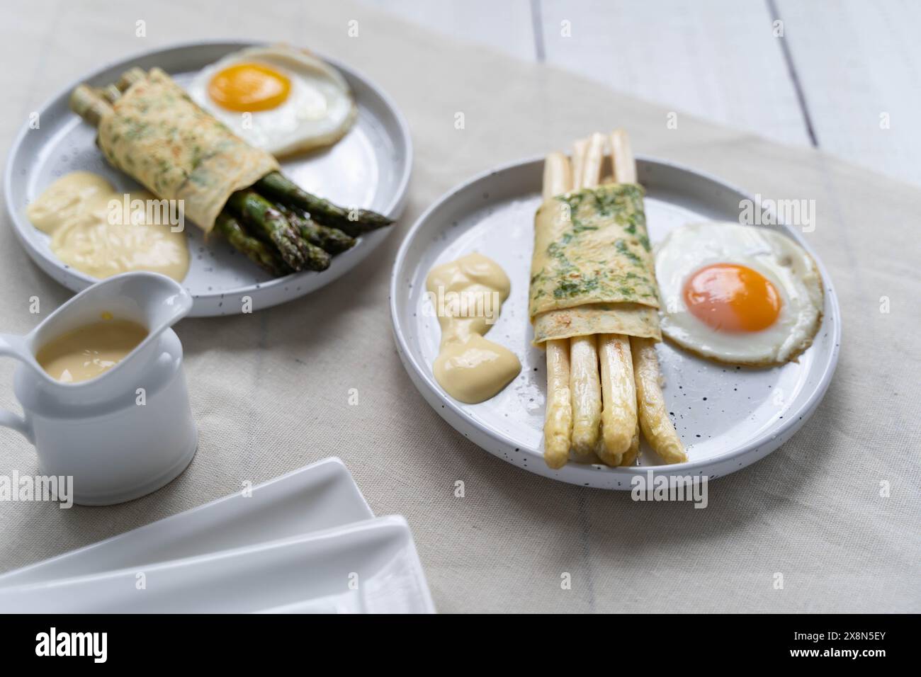 Asperges vertes et blanches enveloppées dans de la crêpe, accompagnées d’œufs au plat. Les asperges représentant les fibres alimentaires sont très populaires en Allemagne pendant Spargelzeit Banque D'Images