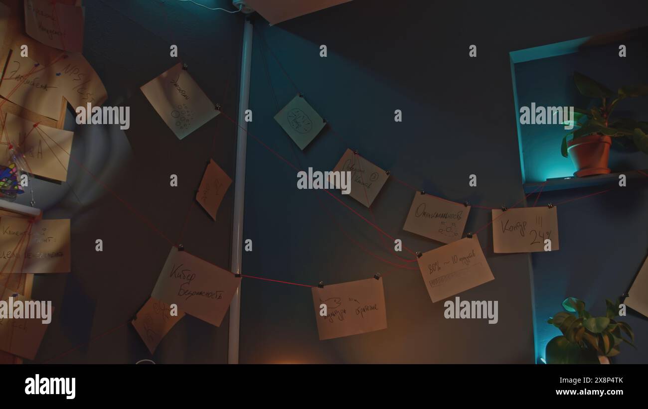 Notes et fils postés. Film de stock. Intérieur de détective avec notes et fil. Notes accrochées sur du fil rouge partout dans le bureau Banque D'Images