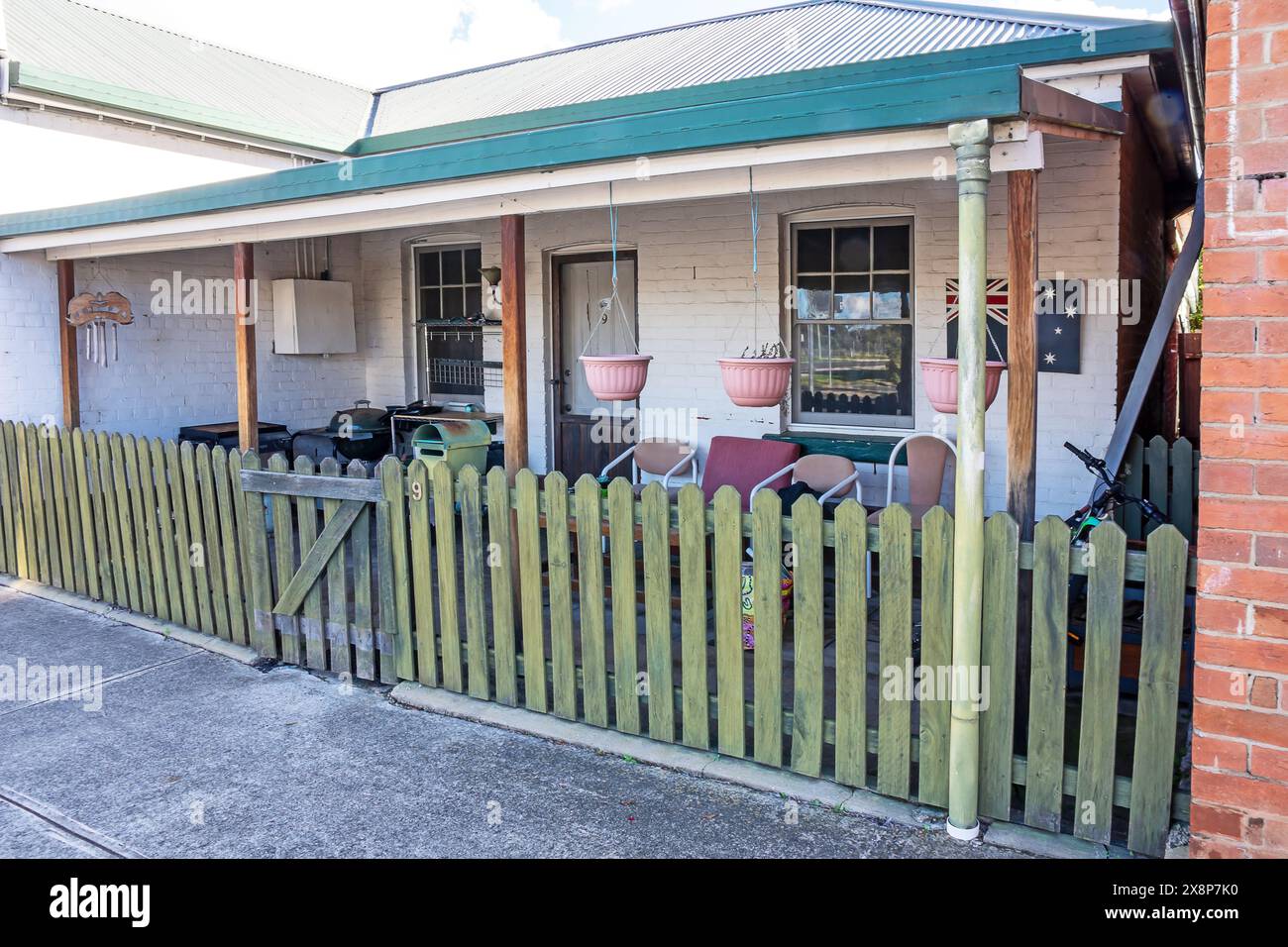 Devant un vieux cottage en briques derrière une clôture de piquetage à Bundarra NSW Australie. Banque D'Images