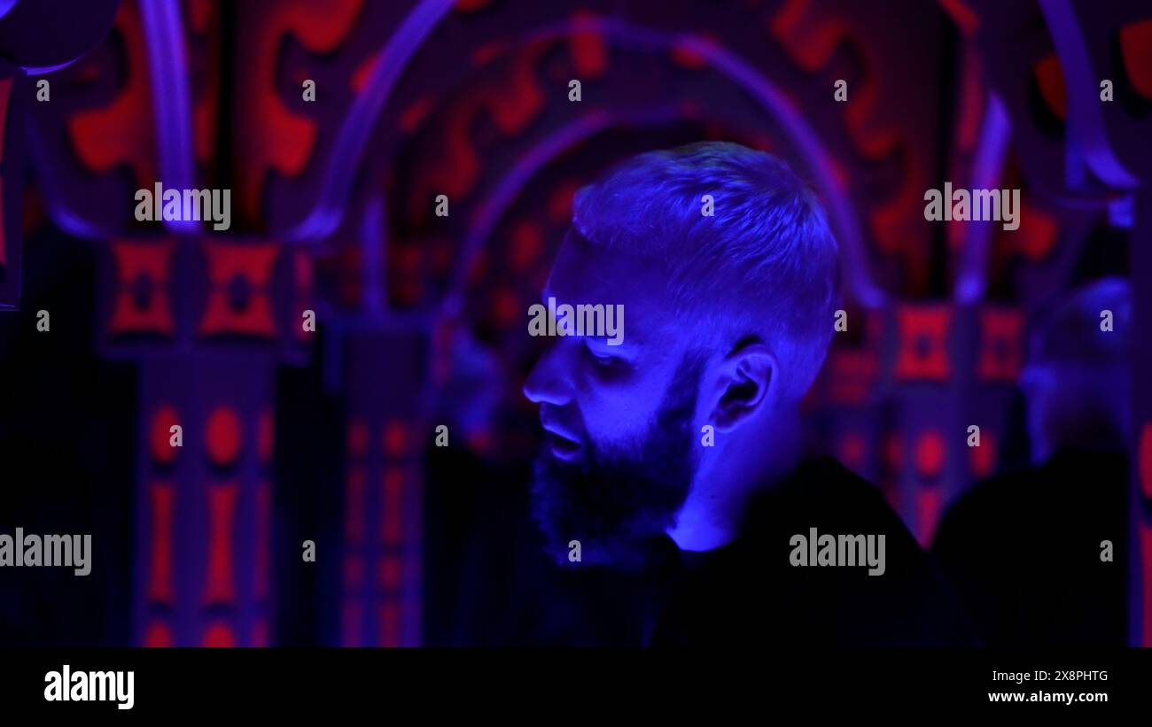 Jeune homme adulte dansant sur la musique électronique, s'amusant et se sentant détendu. Support. Homme avec les yeux fermés sur la piste de danse sous les lumières disco, appréciant Banque D'Images