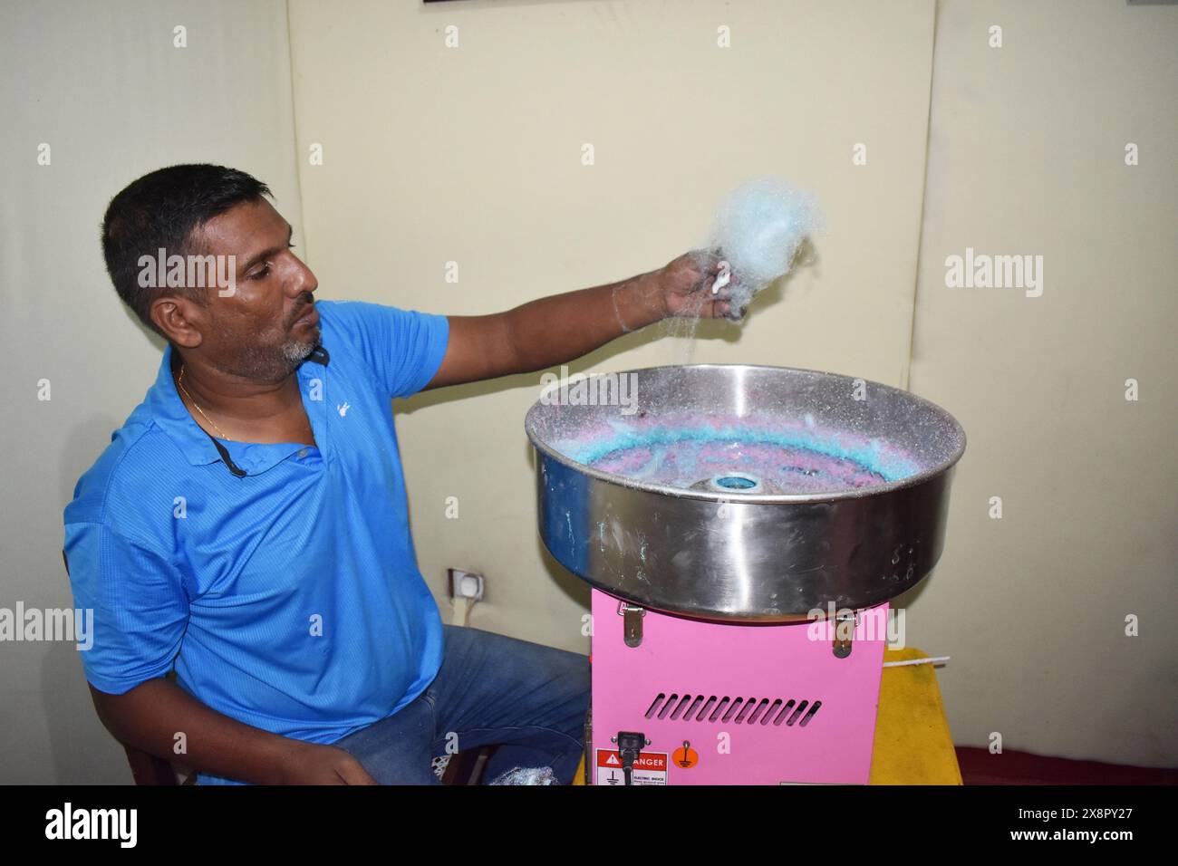 Un homme fabriquant de la soie dentaire de bonbons. La barbe à papa, également connue sous le nom de fil de bonbon et fil de fée, est une confiserie au sucre filé qui ressemble au coton. Il contient généralement de petites quantités d'arôme ou de colorant alimentaire. Colombo, Sri Lanka. Banque D'Images