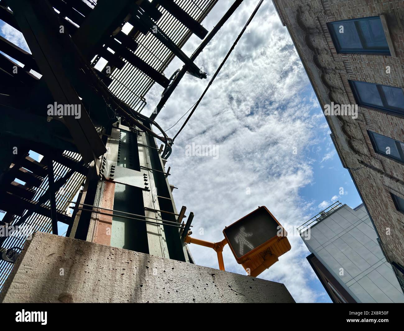 Signal piéton avec des bâtiments et un ciel nuageux dans le Queens, NY Banque D'Images