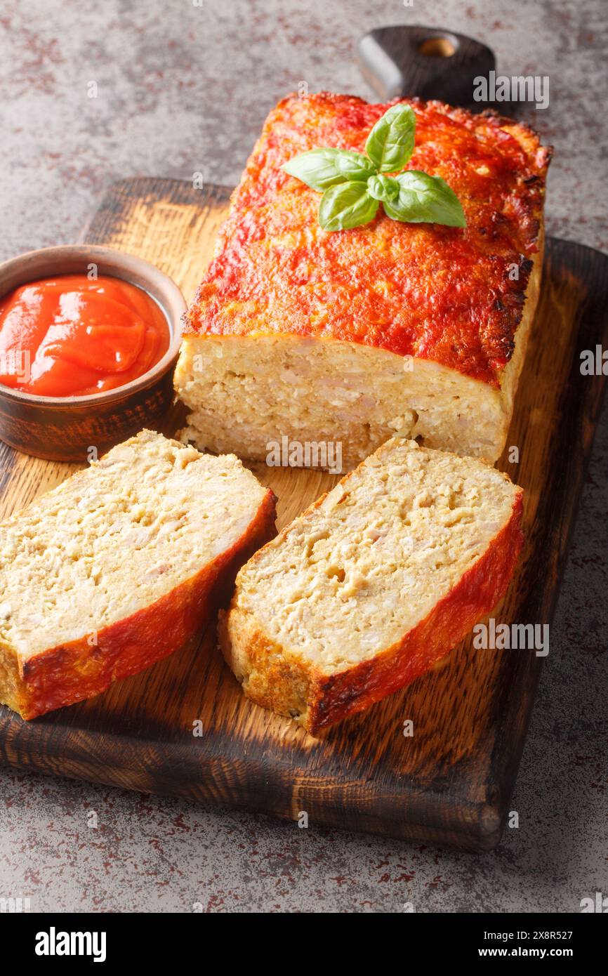 Pain de viande maison ou terrine avec mélange de viande de poulet et de dinde glacé avec ketchup gros plan sur la planche de bois sur la table. Vertical Banque D'Images