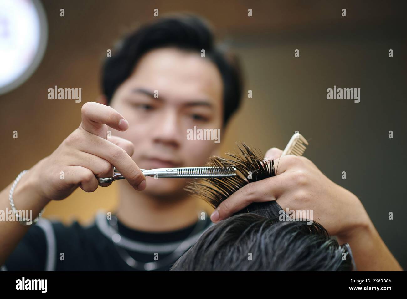 Coiffeur taillant la mèche de cheveux avec des ciseaux de coiffage Banque D'Images