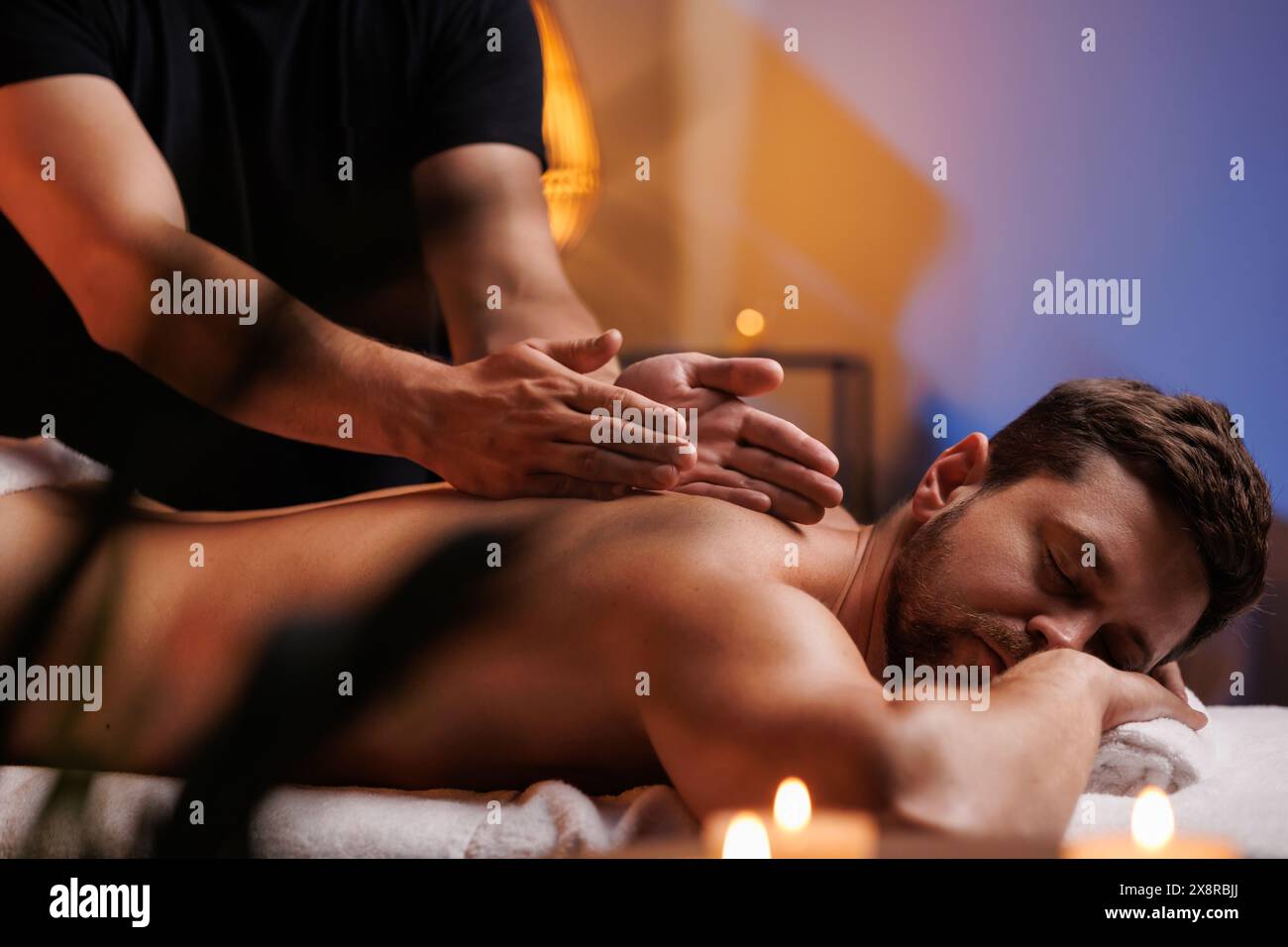 Les mains du masseur masculin frottent activement les visiteurs en arrière, un massage thérapeutique pour les muscles fatigués. Massage ponctuel dans le centre de spa. Corps t Banque D'Images