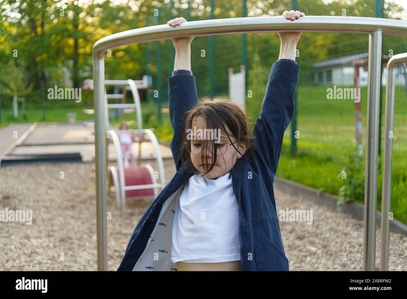 Petite fille écolière dans des lunettes jouit sur une aire de jeux d'été Banque D'Images